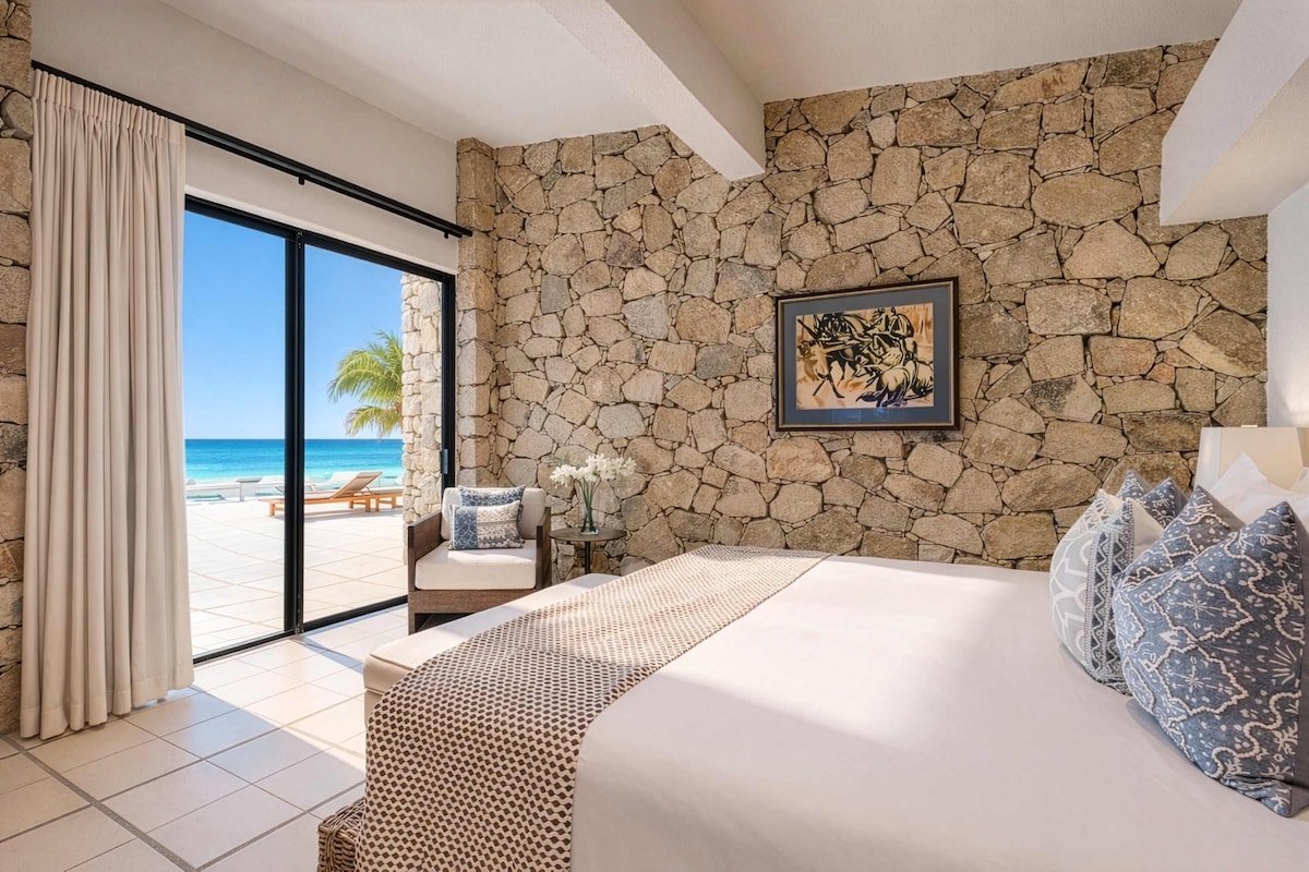 Elegantly appointed king bedroom with stone walls and stunning ocean vistas.