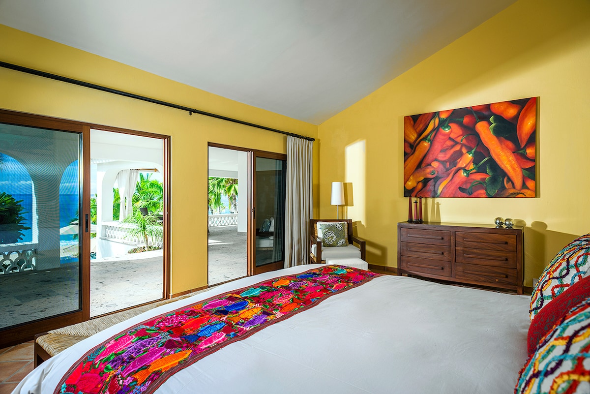 En-suite bedroom with king bed, Mexican artwork and sliding doors to the garden at Casa Edwards, Palmilla
