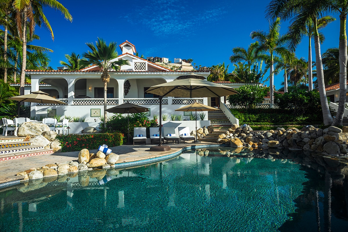 Free-form swimming pool with rock waterfall and the main house at Casa Edwards, beachfront villa in Palmilla, Los Cabos