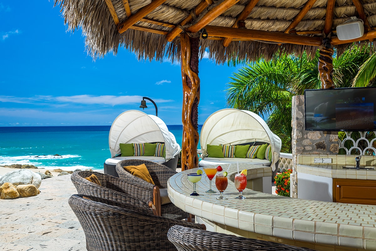 Beach palapa bar with shaded daybeds and television at Casa Edwards, Palmilla, Los Cabos