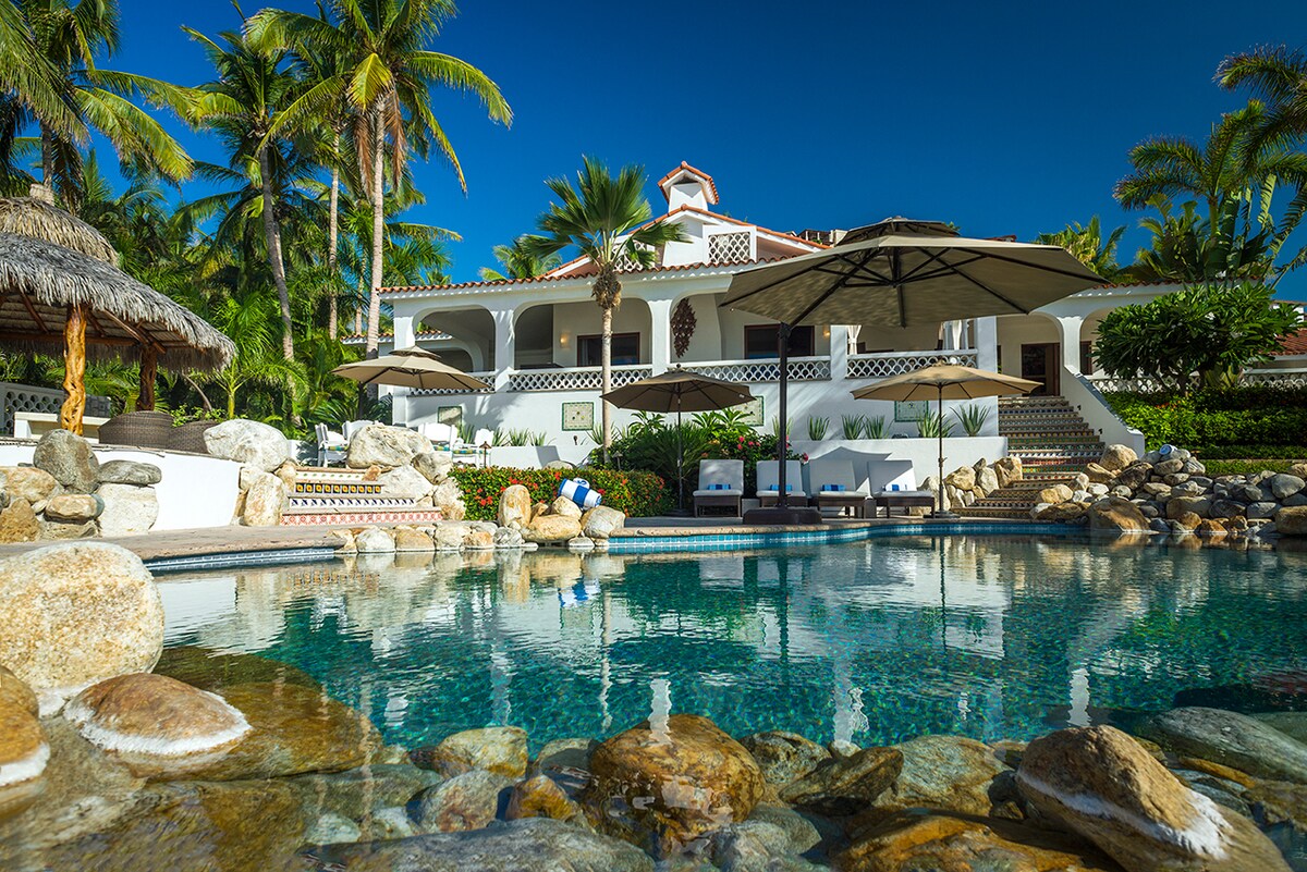 Swimming pool with rock waterfall, umbrellas and the main house at Casa Edwards, Palmilla, Los Cabos