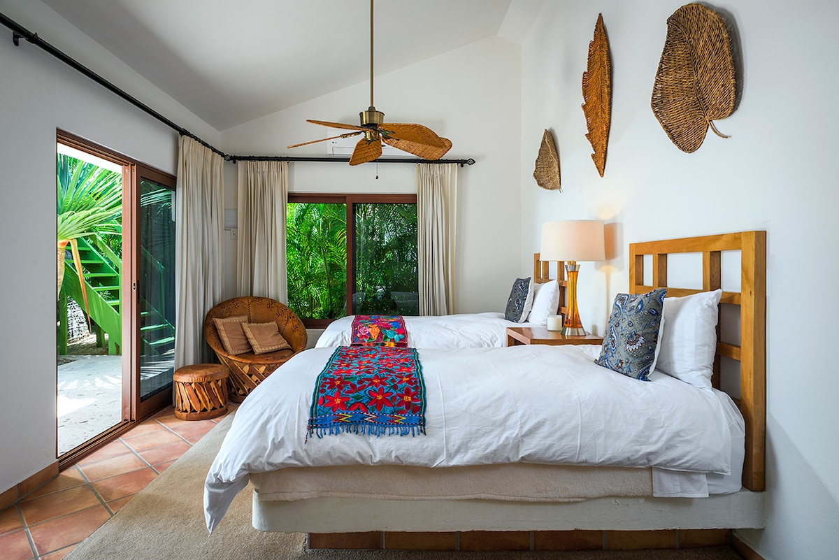 Guest bedroom with carved wood bed and doors onto the tropical garden at Casa Edwards, Palmilla