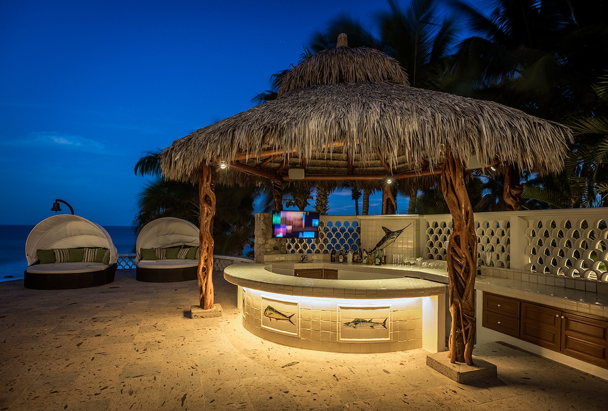 Beach palapa bar lit at night beside the sand at Casa Edwards, Palmilla, Los Cabos