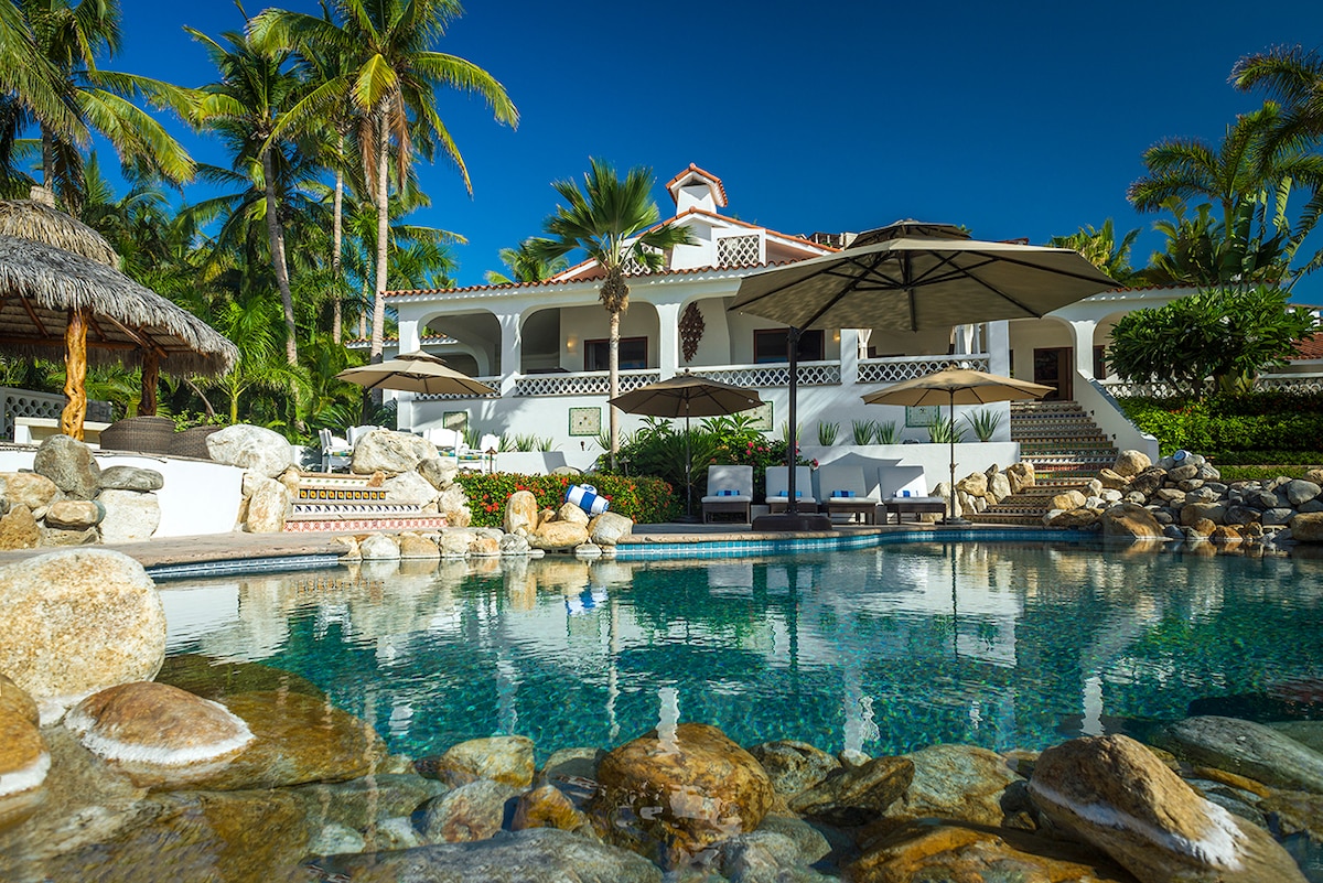 Swimming pool with rock waterfall, umbrellas and the main house at Casa Edwards, Palmilla, Los Cabos