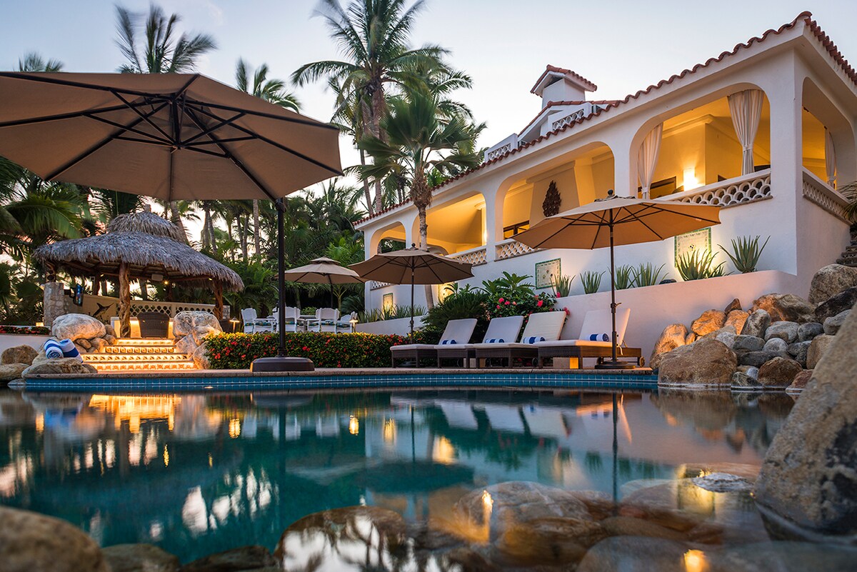 Pool terrace, umbrellas and lit villa at blue hour at Casa Edwards, Palmilla, Los Cabos