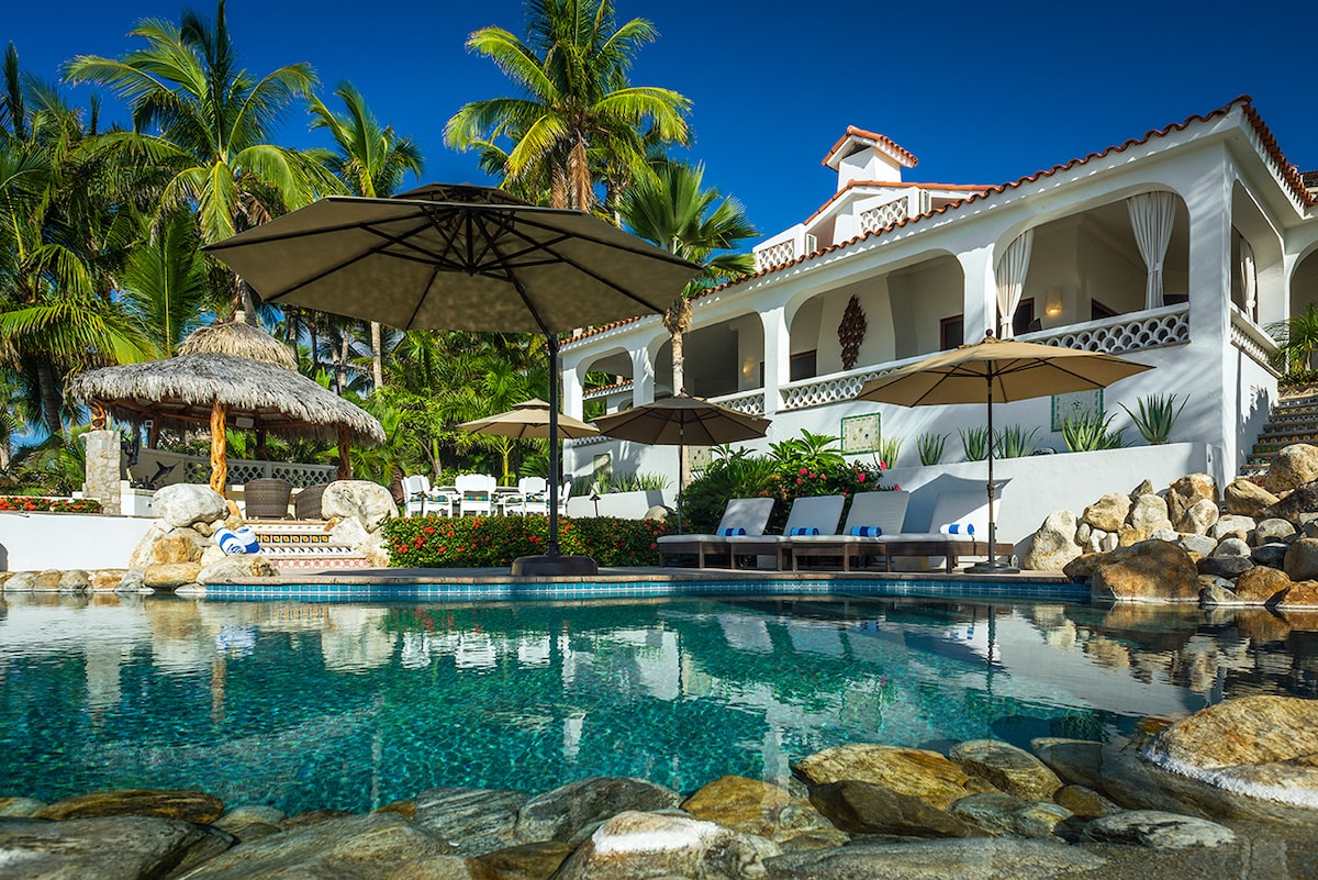 Pool deck with palapa shade, sun loungers and umbrellas at Casa Edwards, beachfront villa in Palmilla